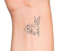 a small tattoo on the wrist of a woman's arm with flowers and a bird