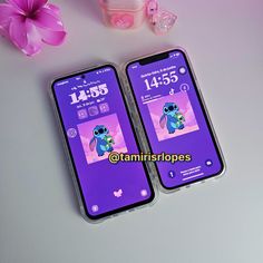 two cell phones sitting next to each other on top of a white table with pink flowers