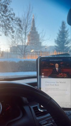 a cell phone sitting on the dashboard of a car in front of a window with a view of a building