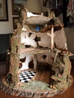 a doll house made out of wood and rocks on top of a table with a checkered floor