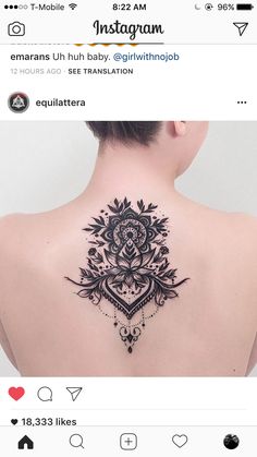 the back of a woman's neck with an intricate tattoo on it