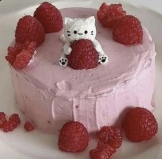 a hello kitty cake with raspberries on the side and some strawberries around it