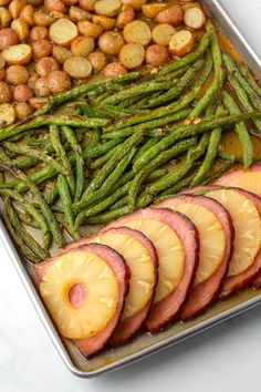 a pan filled with potatoes, green beans and sliced fruit next to other food items