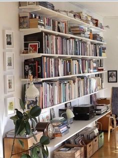 a bookshelf filled with lots of books next to a desk and chair in a room