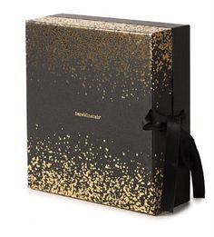 a black box with gold sprinkles and a bow on the front side