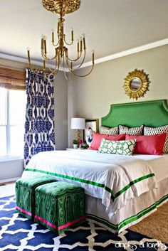 a bedroom decorated in green, white and pink with a chandelier above the bed