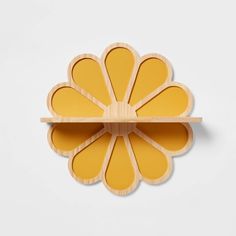 a yellow flower shaped object on a wooden shelf with one section cut out to show it's petals