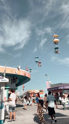 many people are walking around the fairground on a clear day with blue skies above