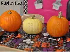 three pumpkins sitting on top of a table next to each other with numbers painted on them