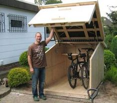 a man standing in front of a shed with his bike attached to the outside wall