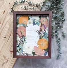 a wooden frame with flowers and greenery on it