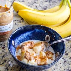 a bowl filled with food next to two bananas and a jar of peanut butter on a table