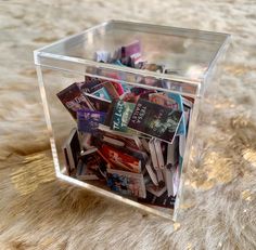 a clear box filled with magazines on top of a fur covered floor