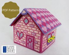 a small pink house made out of knitted fabric with hearts and flowers on the roof