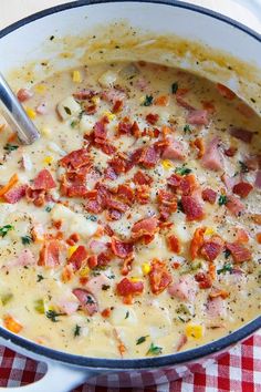 a white bowl filled with ham and cheese soup on top of a checkered table cloth