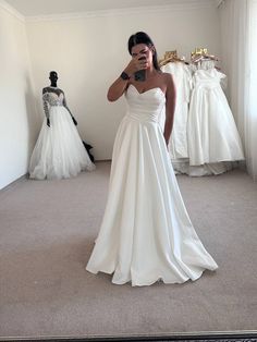 a woman is taking a selfie in front of her wedding dress on the floor