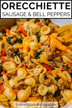 a white bowl filled with sausage and bell pepper pasta next to a wooden spatula