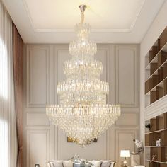 a large chandelier hanging from the ceiling in a living room with white furniture