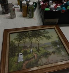 there is a painting on the table with other paint and craft supplies around it,