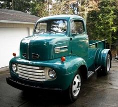 an old green truck parked in front of a house