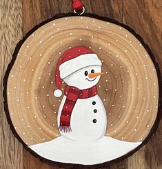 a snowman ornament hanging on a wood slice