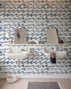 a bathroom with blue and white wallpaper, two sinks and a rug on the floor