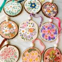 embroidery kits are arranged on wooden slices with ribbons and beads hanging from the handles, along with flowers