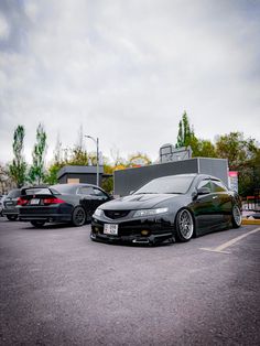 two cars parked in a parking lot next to each other and one is black with chrome rims