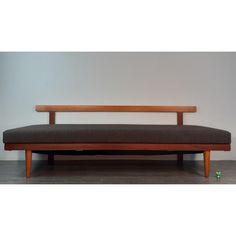 a wooden bench sitting on top of a hard wood floor next to a white wall