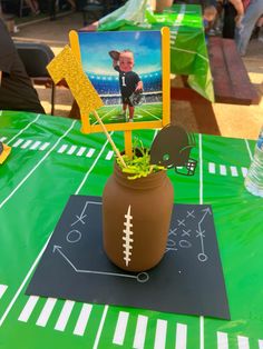 a football themed centerpiece is placed in a vase on a table at a party