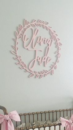 a baby's crib with pink bows and a wall hanging above it that says,