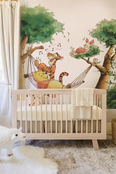 a baby's room with winnie the pooh mural and crib bedding