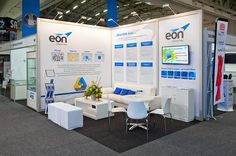 an exhibit booth with white furniture and blue accents on the walls that read eon