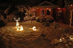 christmas lights are lit up in the front yard of a house on a snowy night