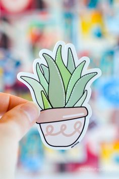 a hand holding up a sticker with a potted plant on it