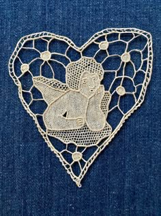 a heart shaped brooch with an angel on it's back, in the shape of a net