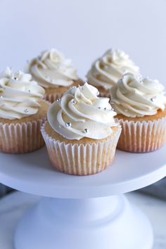 cupcakes with white frosting and sprinkles on a cake plate