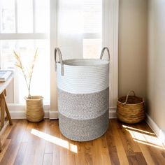 a large white basket sitting on top of a hard wood floor next to a window