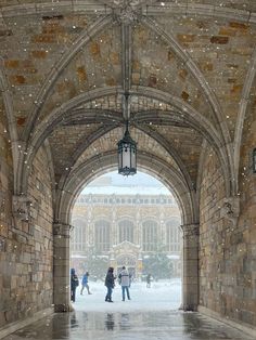 people are walking under an archway in the snow