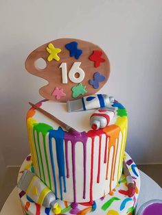 a birthday cake decorated with colorful icing and an artist's palette on top