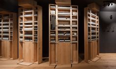 three wooden shelvings with bottles on them in a room filled with wood flooring