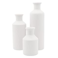 three white vases sitting next to each other on a white surface with no one around them