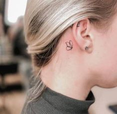 a woman with a small butterfly tattoo on her left side behind the ear, looking down