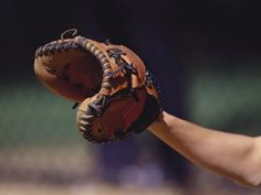 a close up of a baseball glove on a person's hand with the ball in it