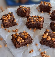 chocolate brownies with nuts on top sitting on wax paper