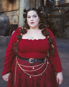 a woman in a red dress with chains around her waist and makeup on her face