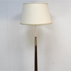 a lamp that is on top of a wooden stand with a white shade over it