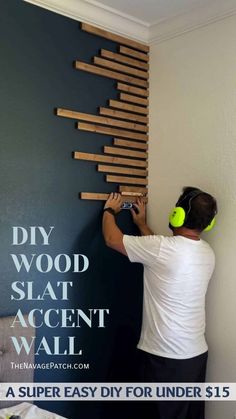 a man is painting the wall with wood slat accent art and headphones on