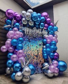 a happy birthday balloon arch decorated with purple, blue and silver balloons in front of a garage door