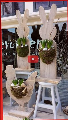 two wooden bunny planters sitting on top of stools in front of a store